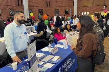 Mercy University student networks with staff and potential employers at 2024 Career Fair