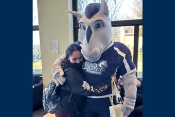 Student hugging Mercy Mascot The Mav