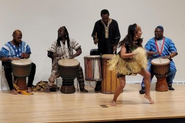 A dancer originally from the Ivory Coast performs with four musicians on the stage at Mercy's Bronx Campus