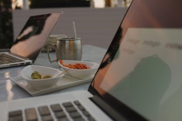 Photo of two open laptops with small plates of food between them.