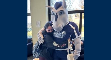 Student hugging Mercy Mascot The Mav