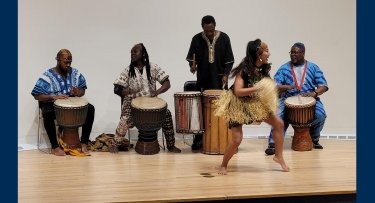 A dancer originally from the Ivory Coast performs with four musicians on the stage at Mercy's Bronx Campus