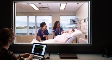 Nursing students in a lab with mannequin
