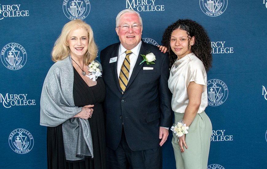 Mrs. Lee Nicholson Hall, President Tim Hall and Student Jade Alers pose in front of a step and repeat the event. 