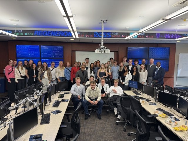 Danish high school delegation and Mercy School of Business professors pose at the trading room